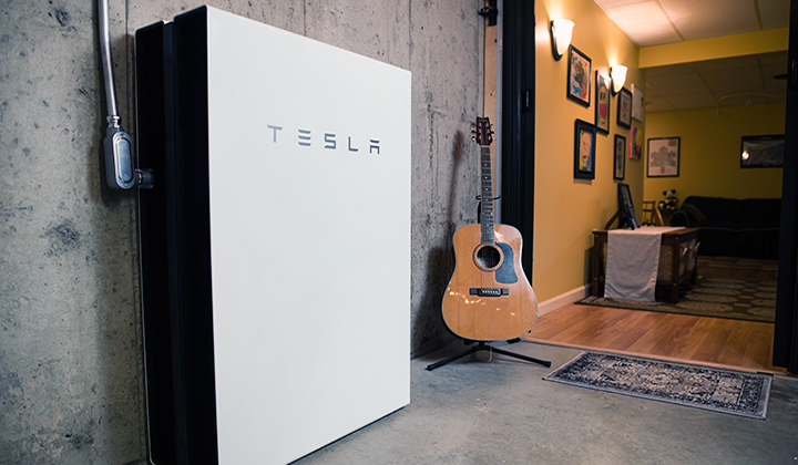 Stacked powerwalls against basement wall with guitar and family room in the background.