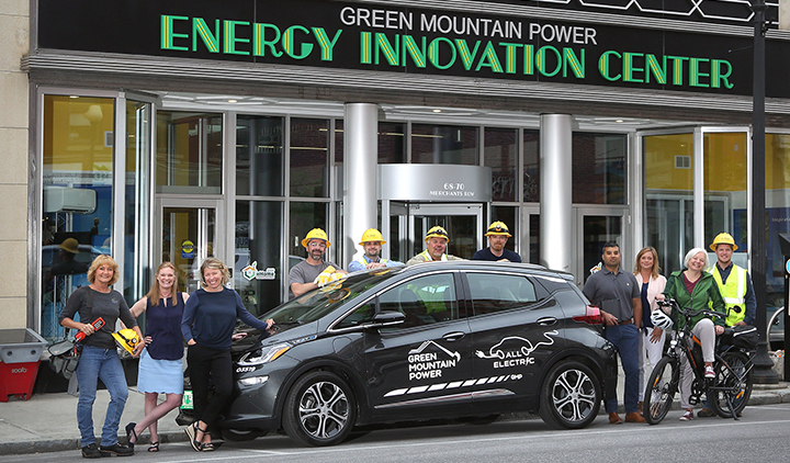 Employees at the Energy Innovation Center around an electric vehicle.