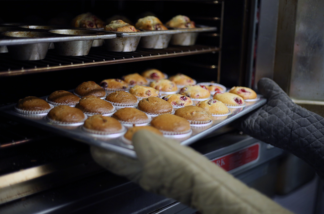 Tin of muffins being removed from commercial oven
