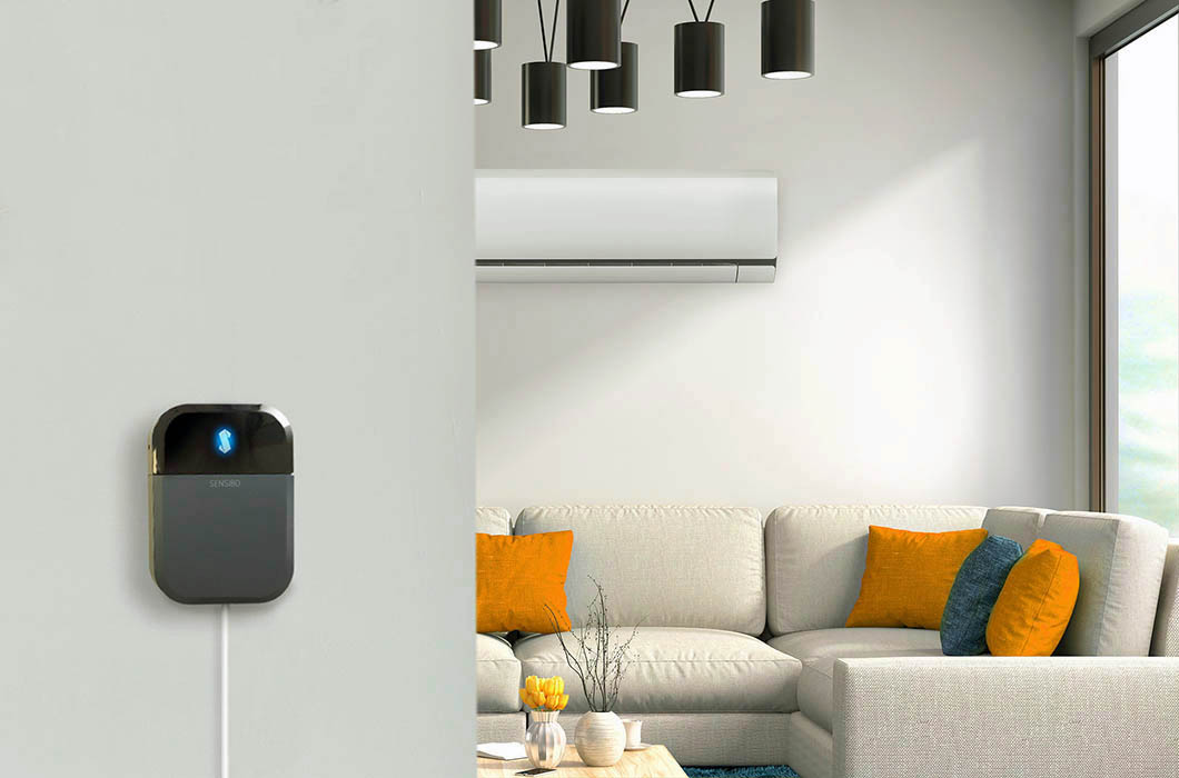 Close up of Sensibo device with living room and heat pump in the background.