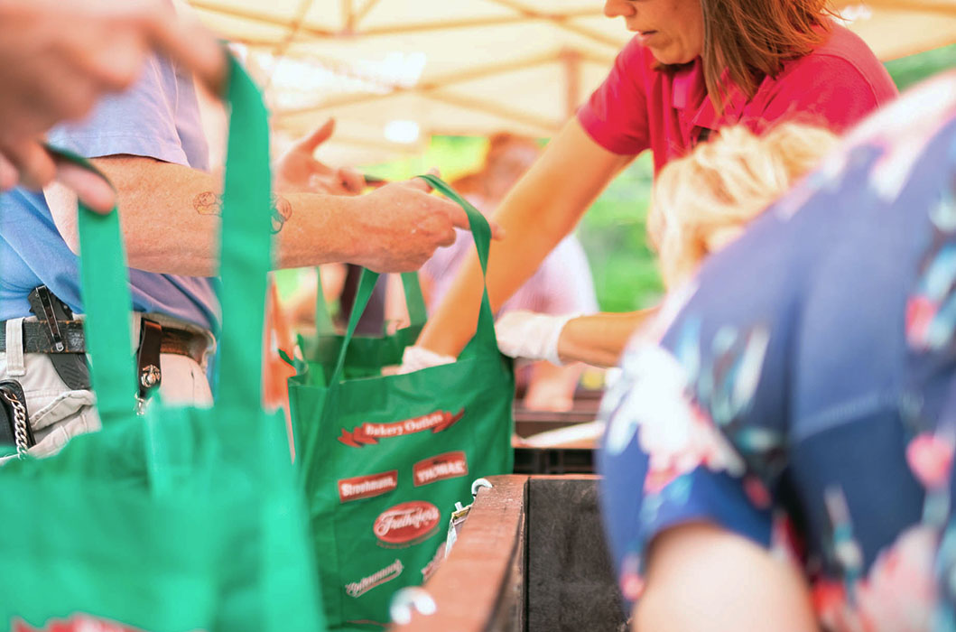 Close-up of shoppers with green canvas bags at vermont food bank.