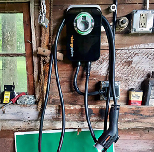 EV charger hanging on interior wall of barn.