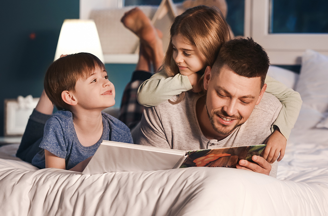 Father and his little children reading bedtime story at home during a storm while Telsa Powerwall keeps the house running.