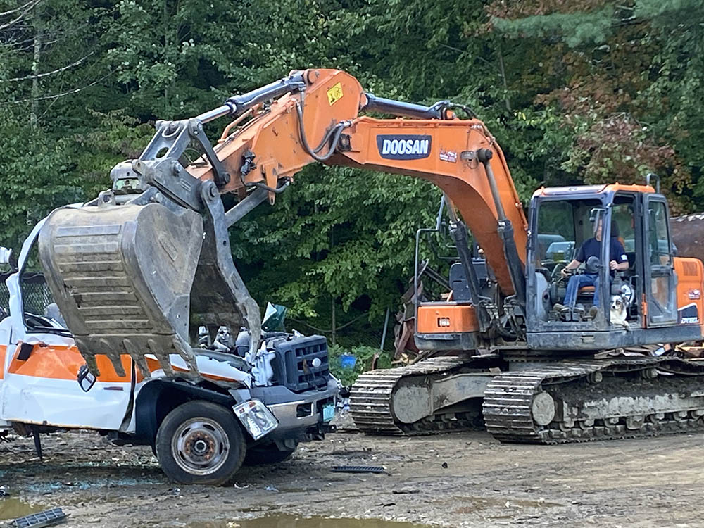 Truck being crushed by excavator.