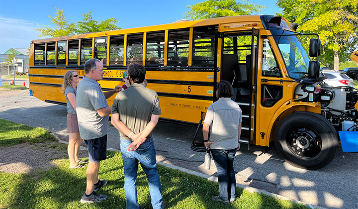 People standing in front of new electric school bus