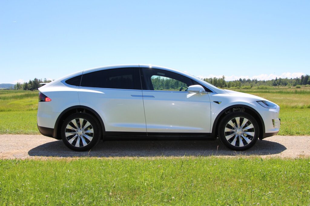 The side of a white Tesla in a field
