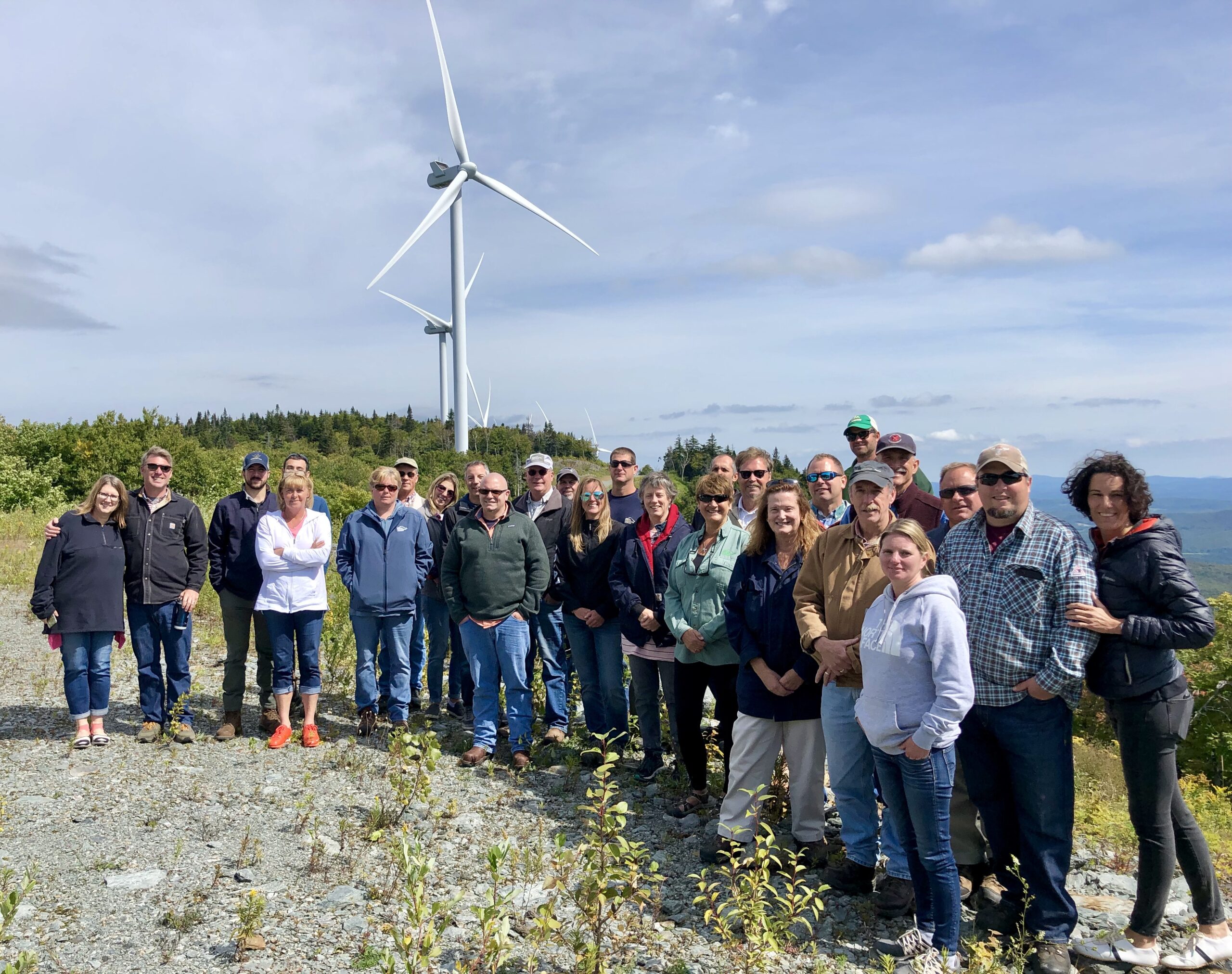 CEO Mari McClure and GMP Distribution Designers in front of wind turbines