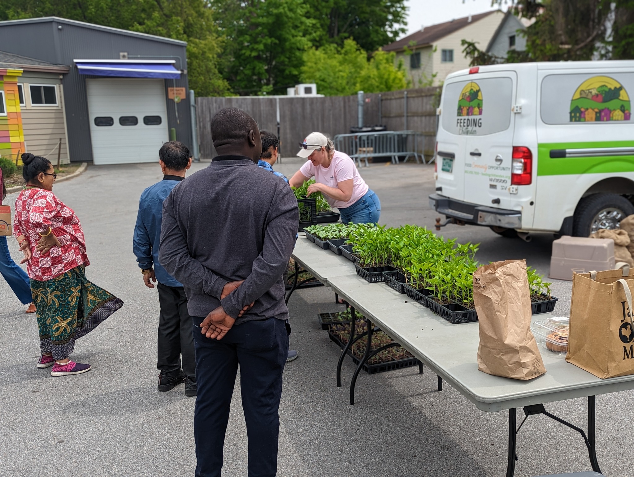 People standing around a table with plants on it, and a van with "Feeding Chittenden" written on it